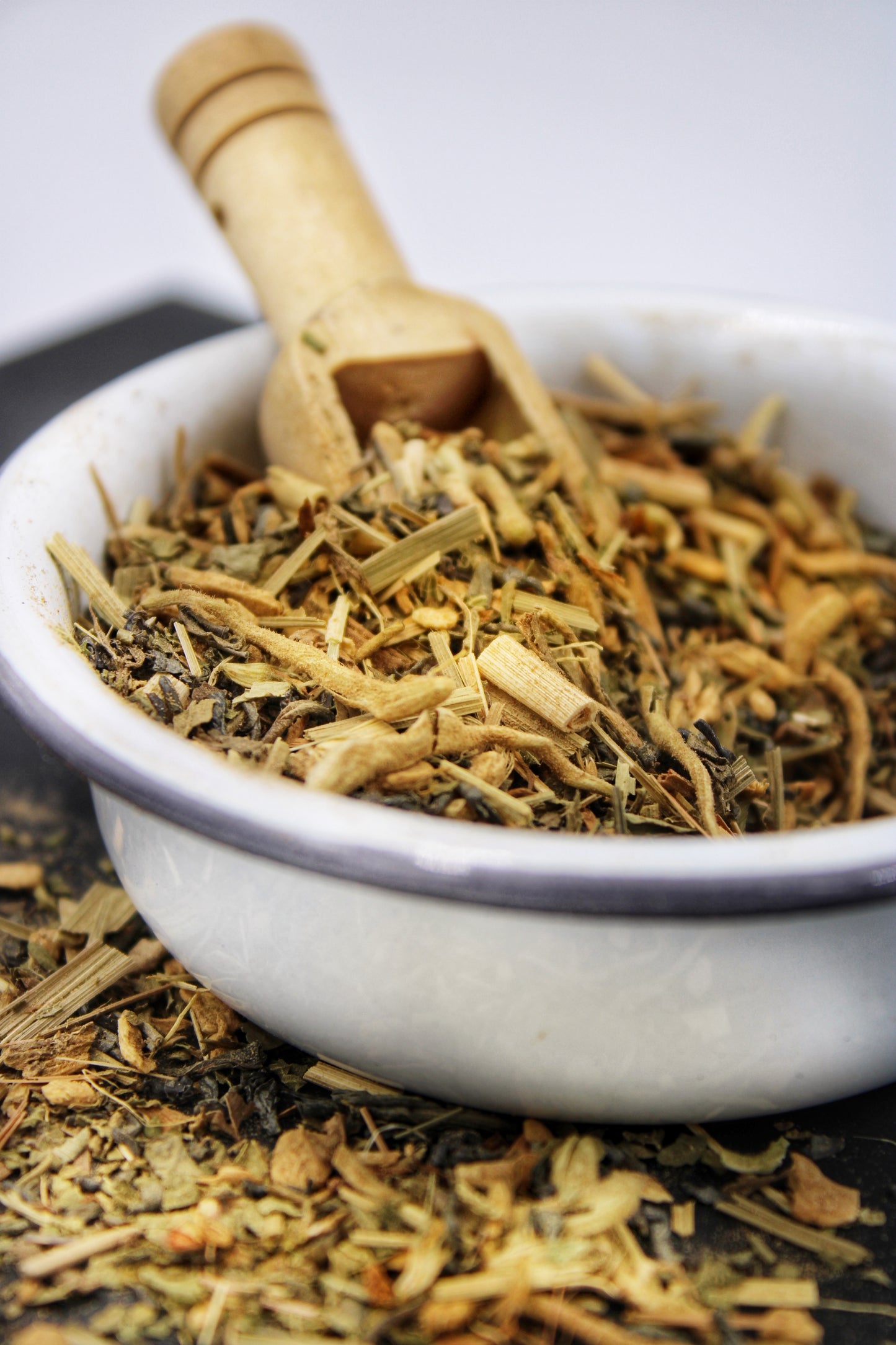 Close-up of Relaxation Tea’s Detox Tea blend in a rustic white bowl with a wooden scoop, highlighting the loose-leaf tea crafted to support the body’s natural detoxification process. This blend is designed to promote wellness and cleansing, aligning with Relaxation Tea’s commitment to high-quality, natural ingredients for a revitalizing tea experience.