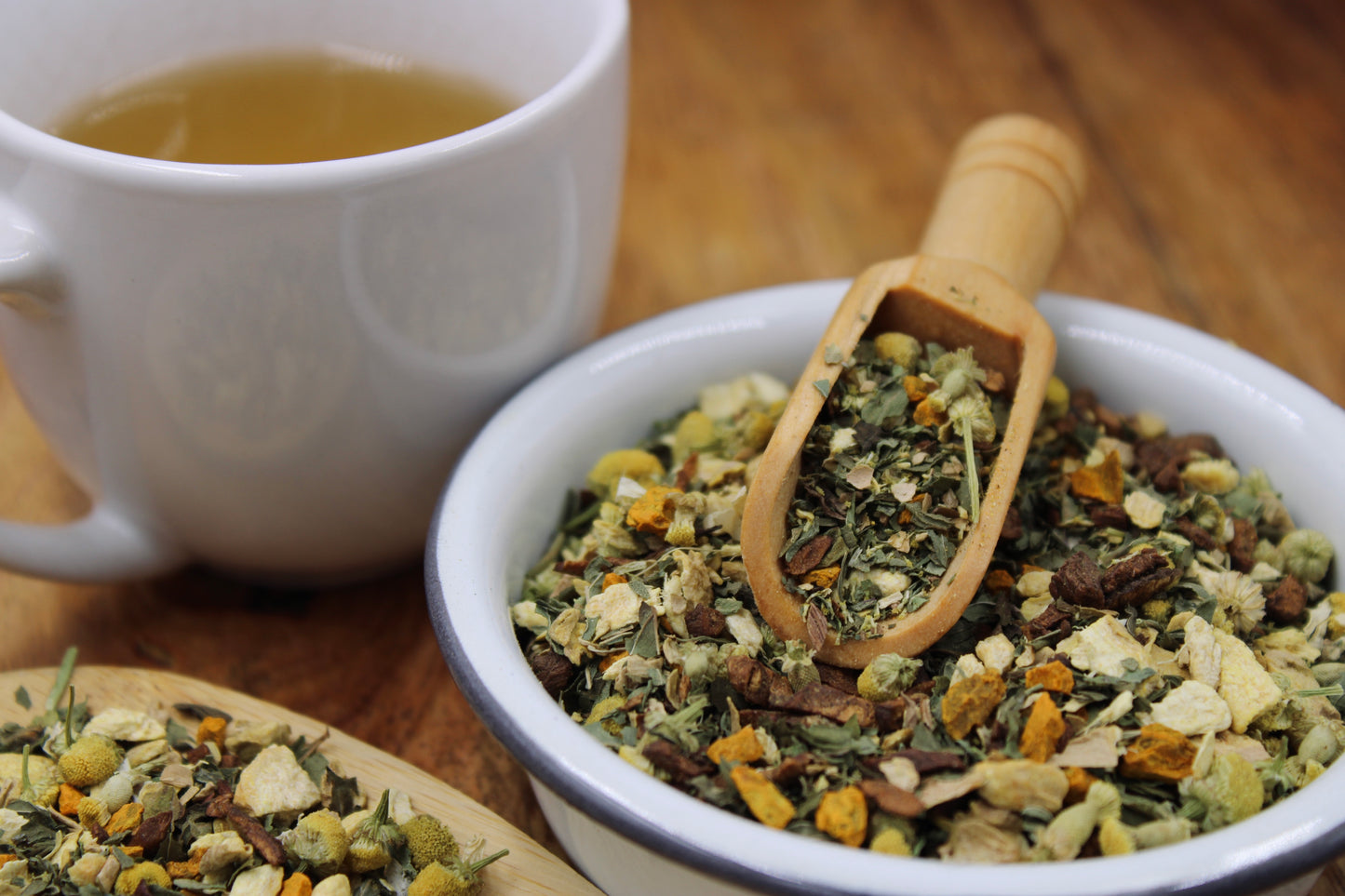 Digestive Tea blend by Relaxation Tea displayed in a white bowl with a wooden scoop, surrounded by loose-leaf herbs and a steaming cup of tea on a wooden surface. This soothing blend is crafted to support healthy digestion and promote gut wellness, showcasing Relaxation Tea’s commitment to natural, high-quality herbal remedies for health-conscious customers.