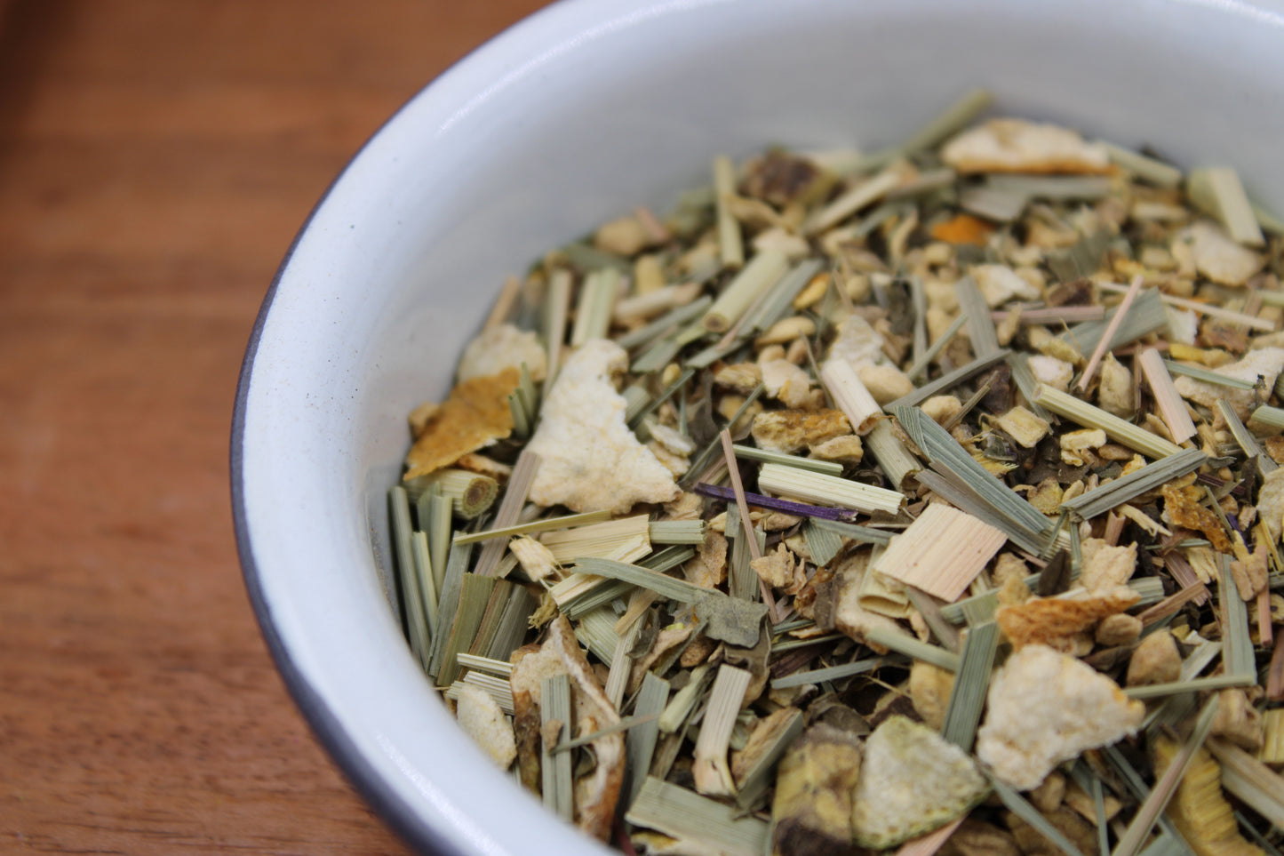 Organic Lemon Ginger Tea blend by Relaxation Tea displayed in a white bowl, showcasing its vibrant loose-leaf ingredients, including organic ginger, lemongrass, lemon peel, licorice root, and spearmint. This refreshing and zesty blend is designed to support digestion and promote soothing relaxation, reflecting Relaxation Tea’s dedication to providing high-quality, organic herbal remedies for tea lovers seeking natural wellness solutions.